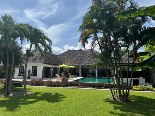 a house with a swimming pool and palm trees at Beautiful Beach Villa Nujum with staff. in Lovina