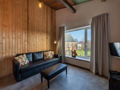 a living room with a couch and a large window at Lovely, modern, 4-person apartment in the heart of Koudekerke in Koudekerke