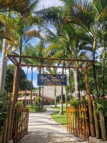 a sign for the entrance to a resort with palm trees at Pousada Vila da Barra in Ilha de Boipeba