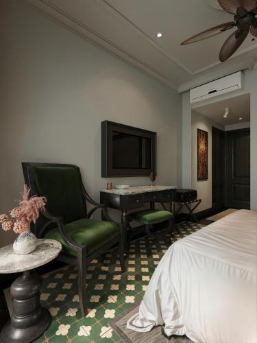 a bedroom with a bed and a desk and a tv at L'Heritage Riverside Hoi An in Hoi An