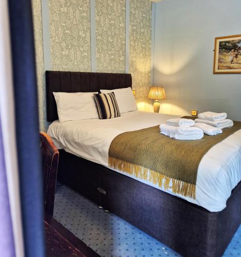 a bedroom with a bed with towels on it at The Devil's Punchbowl Hotel in Hindhead