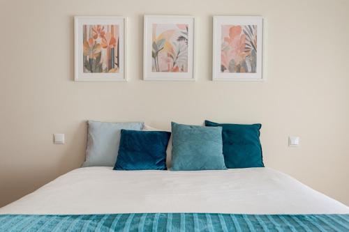 a bedroom with a bed with three pictures on the wall at GuestReady - Stylish City Centre Flat with Parking in Maia