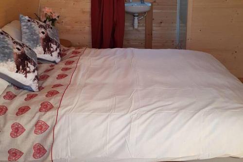 a bed with a white comforter with hearts on it at Glamping Pod in St Austell Sleeps 2 with Spa Pool in Lanivet