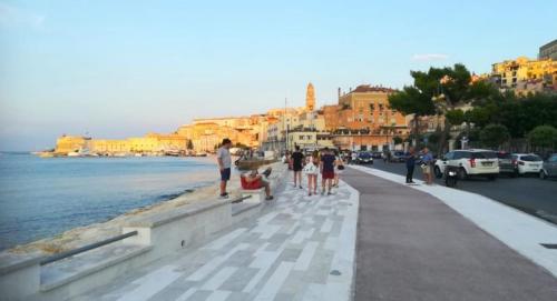 a group of people standing on a sidewalk near the water at A Due Passi Dal Mare - Serapo in Sèrapo