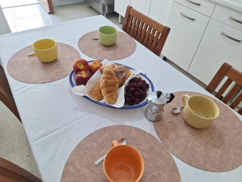 a table with two cups and a bowl of fruit at A Due Passi Dal Mare - Serapo in Sèrapo