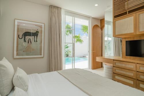 a bedroom with a bed and a tv and a window at Nisí Villas Bingin, Uluwatu in Uluwatu