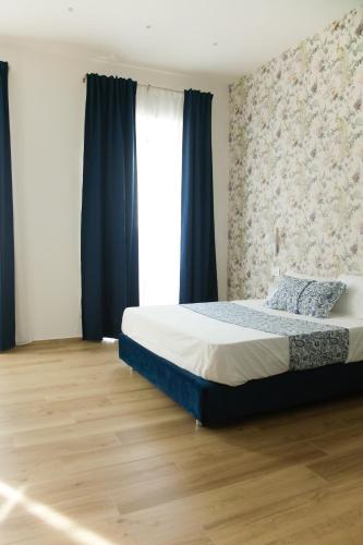 a bedroom with a bed with blue curtains and a window at Dimora Luminè in Naples