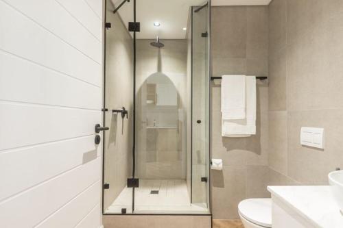 a bathroom with a shower with a toilet and a sink at On Park - Century City Lux Studio Apartment in Cape Town