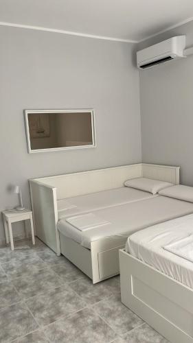 a white bedroom with two beds and a table at Annarè Home in Vasto