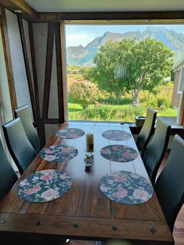 a wooden table with four plates and a glass of wine at Fredvang - 5 bedrooms Feriehus - Lofoten in Fredvang