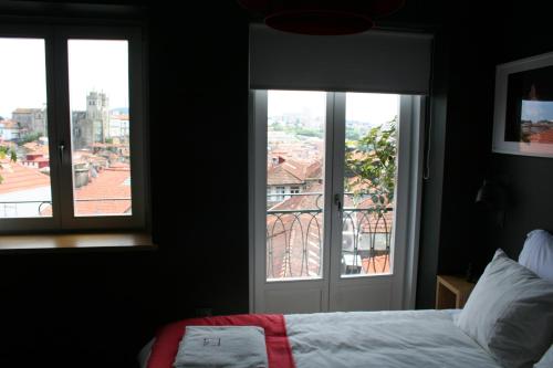 a bedroom with a bed and two windows with a view at 2U Oporto Urban Stays in Porto