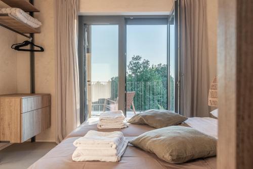 a bedroom with a bed with towels on it with a window at Casa San Verde Hill in Novaki Motovunski