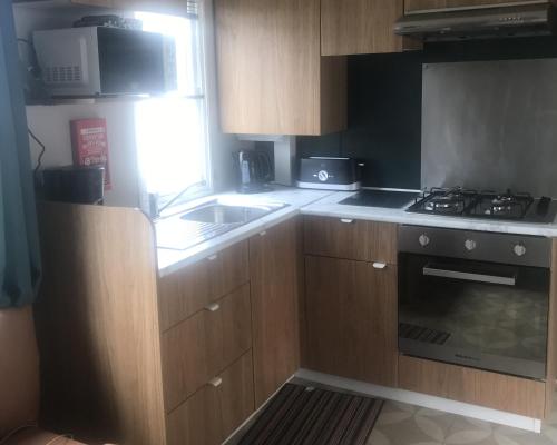 a kitchen with wooden cabinets and a stove top oven at Le Domaine de Litteau 4 étoiles à LITTEAU emplacement 443 3CH 1SDB 6 personnes in Litteau