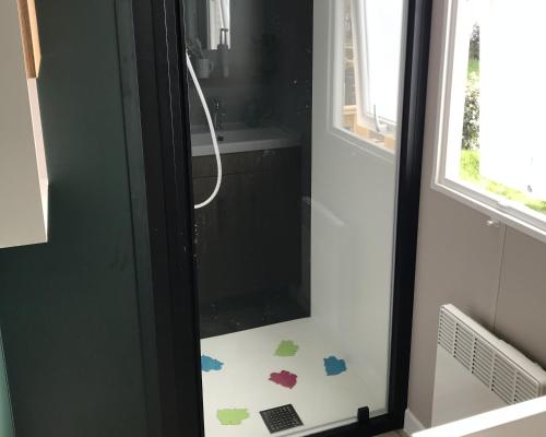 a bathroom with a shower with stickers on the door at Le Domaine de Litteau 4 étoiles à LITTEAU emplacement 443 3CH 1SDB 6 personnes in Litteau
