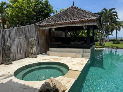 a small swimming pool with a gazebo next to a swimming pool at Beautiful Beach Villa Nujum with staff. in Lovina