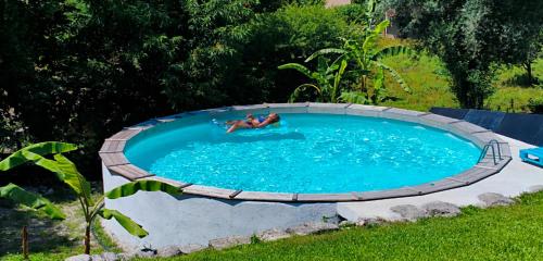 a person laying in a circular pool in a yard at Casa Nova das Oliveiras in Braga