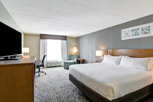 a hotel room with a bed and a flat screen tv at Holiday Inn Express & Suites Oshawa Downtown - Toronto Area by IHG in Oshawa