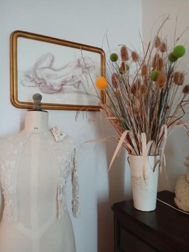 a dress and a vase on a table with a mirror at Chambres D'hôtes Au Gré Du Temps in Saint-Aignan