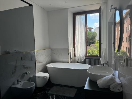 a white bathroom with a tub and two sinks and a window at Relais Stibbert Florence in Florence