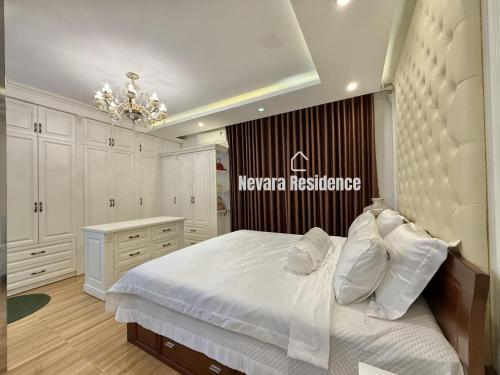 a bedroom with a large white bed and a chandelier at Nevara Residence Hue in Cồn Giả Viên