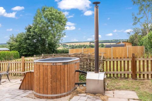 a wooden barrel smoker in a backyard with a fence at Unplug & Reconnect, Romantic Retreat with Hot Tub in Yarpole