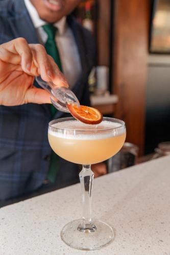 a person is putting an orange slice into a cocktail at Holiday Inn Belfast by IHG in Belfast