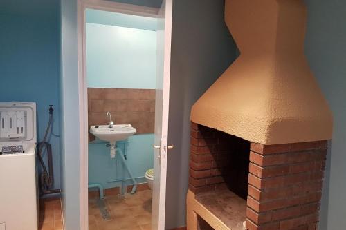 a bathroom with a brick fireplace and a sink at Maisons agréables 13ms024 in La Fresnais