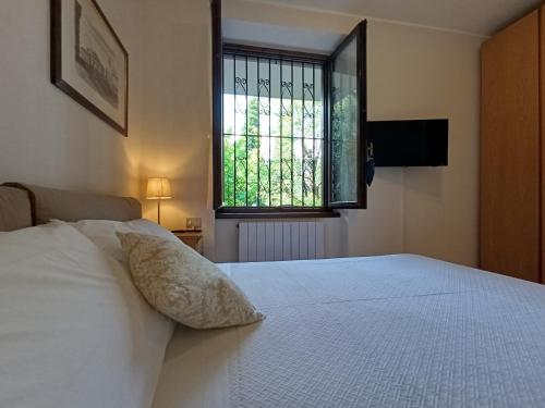 a bedroom with a white bed with a window at Portico sul lago in Oliveto Lario