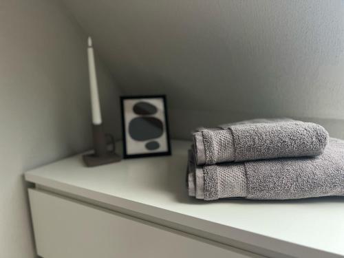 two towels on a shelf with a picture and a candle at studio lb 11 Moderne, helle Dachwohnung am Rande der Schwäbischen Alb in Bartholomä