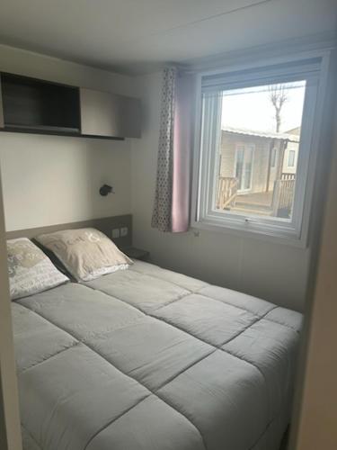 un lit dans une chambre avec une fenêtre dans l'établissement MOBIL HOME l'ETOURNEAU, à Valras-Plage