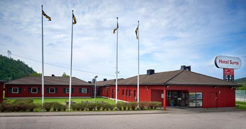 a red building with flags in front of it at Hotel Surte in Surte