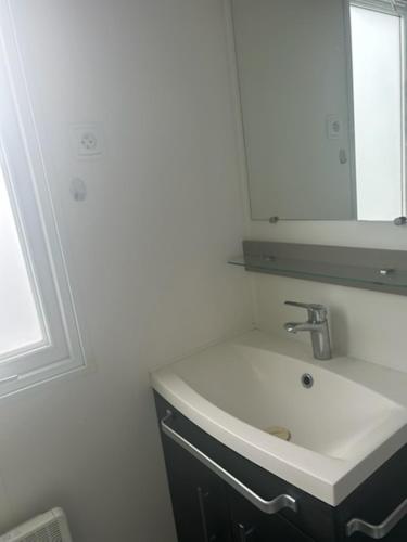 une salle de bain blanche avec un lavabo et un miroir dans l'établissement MOBIL HOME l'ETOURNEAU, à Valras-Plage