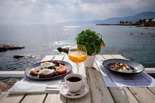 una mesa con dos platos de comida y un vaso de jugo de naranja en Glaros Royal Beach Hotel, en Hersonissos