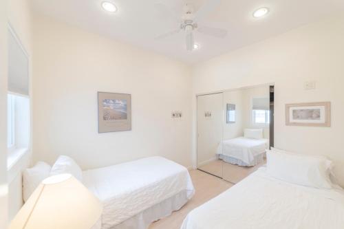 a white room with two beds and a mirror at The Hermitage at Napeague in Amagansett