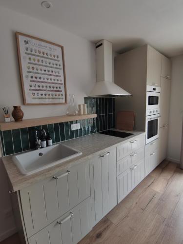 a kitchen with white cabinets and a sink at Le chai de Francky et Lilie in Pauillac