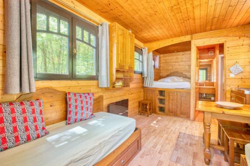 une chambre en rondins avec un lit et un bureau dans l'établissement La Roulotte Jaune, à Monsac