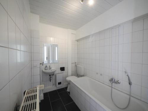 un bagno bianco con vasca e lavandino di Monteurwohnung-mit-Terrasse-fuer-7-Personen-WLAN-TV-Kueche-Ahrensburg-Naehe-Hamburg-OD06c a Ahrensburg