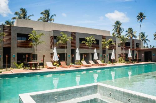 a pool at a hotel with chairs and umbrellas at Vilas Manatee - Praia do Patacho in Pôrto de Pedras