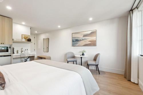 a bedroom with a white bed and a table and chairs at Casa Riviera - Boutique Suites in Downtown Santa Barbara in Santa Barbara