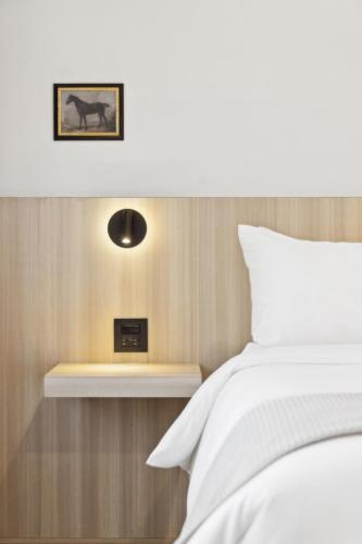a bedroom with a white bed and a clock on a shelf at Casa Riviera - Boutique Suites in Downtown Santa Barbara in Santa Barbara