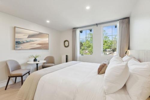 a white bedroom with a large bed and windows at Casa Riviera - Boutique Suites in Downtown Santa Barbara in Santa Barbara