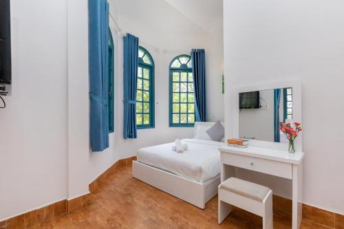 a bedroom with a bed and a desk and windows at Lotus Luxury Villa Da Lat in Da Thien