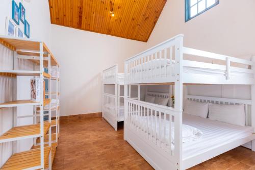 a room with white bunk beds and wooden ceilings at Lotus Luxury Villa Da Lat in Da Thien