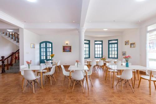 a dining room with white tables and white chairs at Lotus Luxury Villa Da Lat in Da Thien