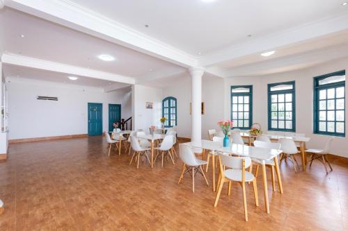 a dining room with white tables and chairs at Lotus Luxury Villa Da Lat in Da Thien