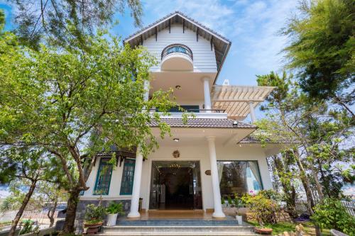 a white house with trees in front of it at Lotus Luxury Villa Da Lat in Da Thien