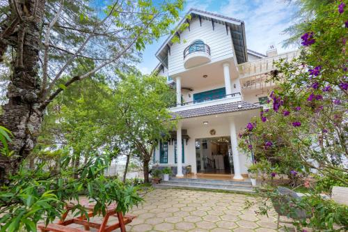 an exterior view of a white house with trees at Lotus Luxury Villa Da Lat in Da Thien