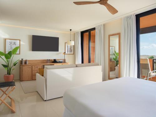 a bedroom with a white bed and a television at H10 Costa Adeje Palace in Adeje