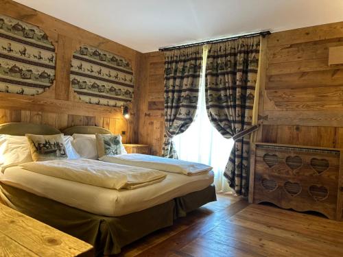 a bedroom with a bed in a room with wooden walls at Hotel La Rouja in Champoluc