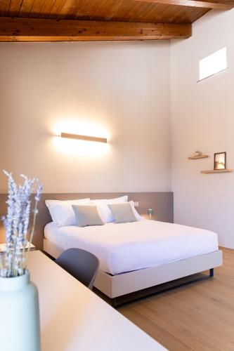 a bedroom with a white bed and a table at RESPIRA - rooms & apartments in Serralunga d'Alba